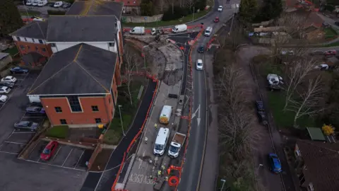Wiltshire Council An aerial view of cars, white vans, a red building.
