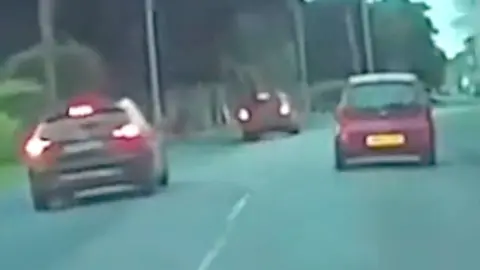 Car overtakes two other cars on the wrong side of the road.