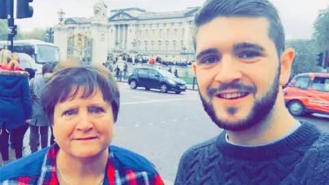 Kieran Hutcheon Larraine Hutcheon pictured with her son Kieran in a smiling selfie, with Buckingham Palace in the background.