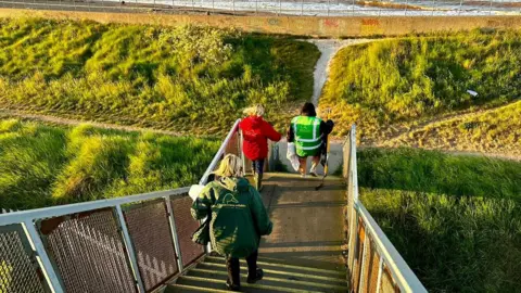 Cleethorpes Wildlife Rescue People walking down steps which lead to a beach. One is wearing a high-vis jacket.