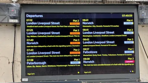 A digital train announcement board showing services with cancelled or delayed labels. 