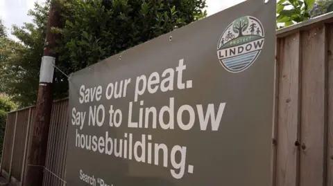 A large grey banner banner with white writing on it which reads: "Save our peat. Say NO to Lindow housebuilding."