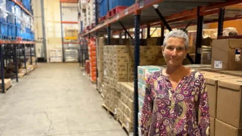 Nell Miller stands in front of warehouse boxes