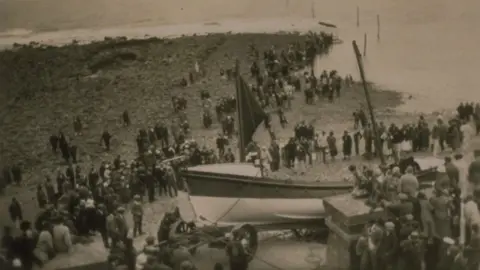 RNLI Old image of the Overland Launch. The Louisa can be seen at the shore, with lots of people nearby.