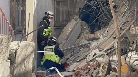 Serve On Volunteers in uniform and helmets searching in rubble