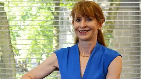 Lancashire County Council Angie Ridgwell, smiling, in front of a window 