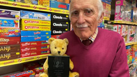 Clive Brown in his shop holding the award