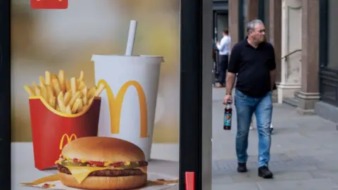 Getty Images A man walks past a McDonald's ad in July 2023 in the UK