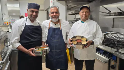 Hayley Coyle/BBC Vivek and some of his team ahead of the big opening standing in a hotel kitchen dressed in chef's whites and holding spices