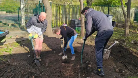 Friends of Lee Coates helping to dig a hole for a pond at Huntingdon Academy in Nottingham