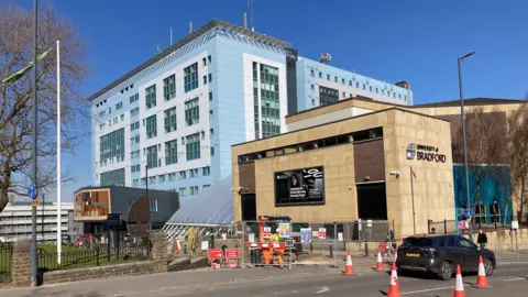 A blue building and a yellow stone building next to each other with a road running in front.