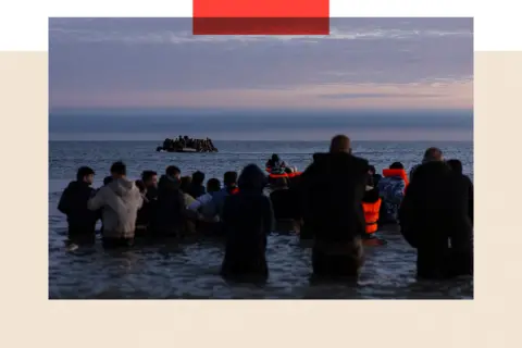 Getty Images Migrants wait in the water to board a boat across the English Channel