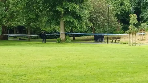 Paul Hayes/BBC Police officer in Chapelfield Gardens stood next to a police cordon