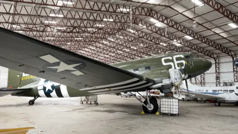 The former US transport plane christened Night Fright by its wartime crew stands inside an aircraft hangar.