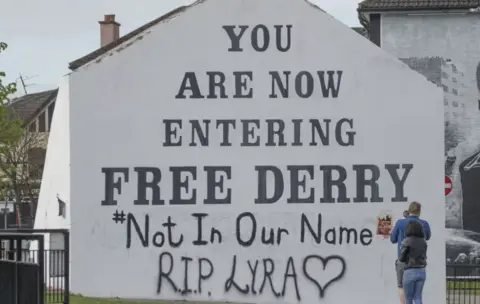 PA Free Derry Corner, a large white gable wall which reads: 'You are now entering Free Derry #NotInOurName RIP Lyra' 