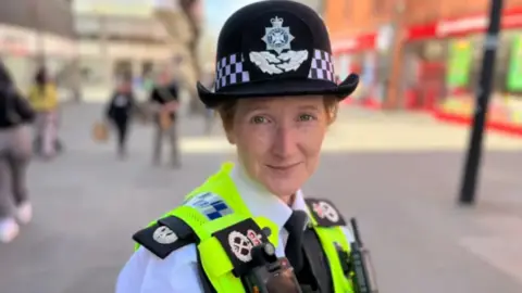 A woman in a black police hat and wearing a high-vis jacket