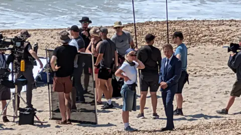 BBC Film crews on a beach in Dorset near the sea on a sunny day