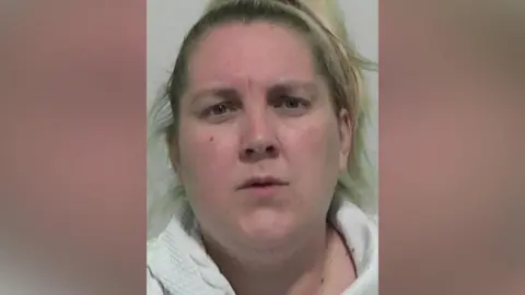 Mugshot of Joanne Nicholson. She has blond hair pulled back into a ponytail and looks surprised.