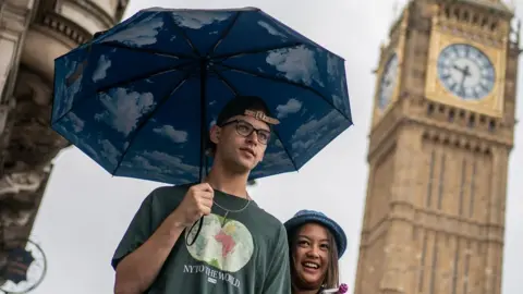 PA Media Man holding an umbrella near Big Ben with a woman.