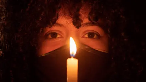 EPA A woman holds a candle during a protest in Brasilia