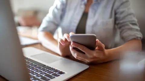 Getty Images Woman using phone and laptop