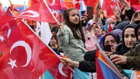 ADEM ALTAN/AFP  Supporters of Turkish President Recep Tayyip Erdogan wave Turkish flags and cheer during his election campaign rally in Ankara, on April 30, 2023