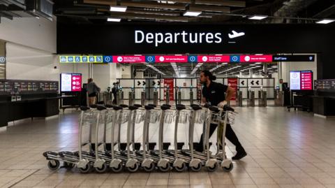 Man pushing airport trolleys