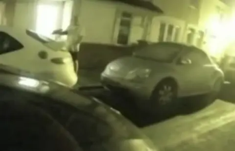 Man holding gun stood near cars