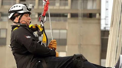 Then- Prince Andrew dangling on a rope wearing a hard hat