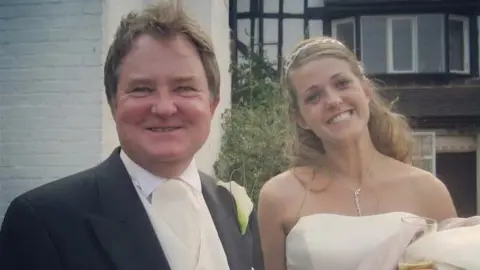 Amy Dickson Amy Dickson on her wedding day, wearing a white dress and smiling, standing beside her dad Steve, who is wearing a morning suit.