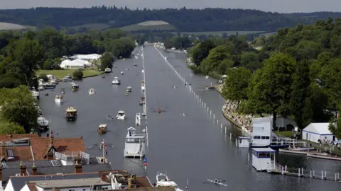 PA Media A picture of the course at the Henley Royal Regatta, with a course clearly marked along the river and other boats positioned alongside it.