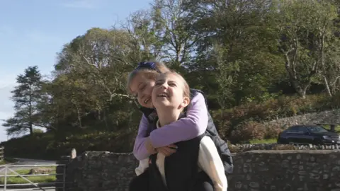 Betsy on her sister Tilly's back in the grounds of Ogmore castle 