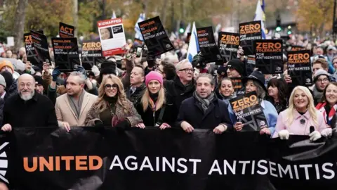 Jordan Pettitt/PA Chief Rabbi Mirvis, Eddie Marsan, Tracey-Ann Oberman, Rachel Riley, Maureen Lipman and Vanessa Feltz take part in a march against antisemitism organised by the volunteer-led charity Campaign Against Antisemitism at the Royal Courts of Justice in London