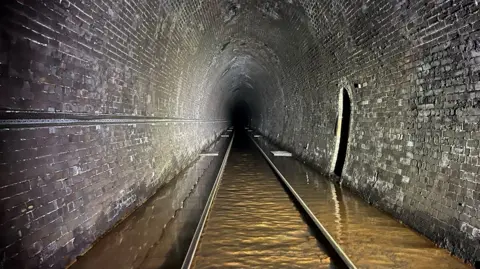 Network Rail Brown coloured floodwater on the tracks of the Bransty tunnel.