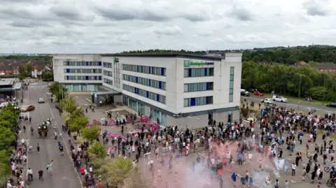 Reuters A drone view shows demonstrators protesting outside a hotel as police officers stand guard in Rotherham,