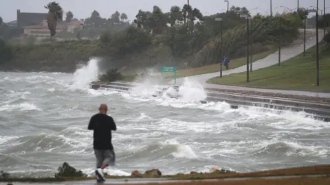 walks near the bay waters as they churn from approaching Hurricane Harvey on August 25, 2017 in Corpus Christi, Texas