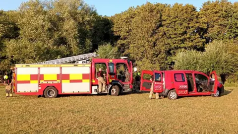 Fire crews disembarking from a fire engine and van.