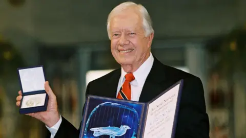 Getty Images Jimmy Carter holds up his Nobel Peace Prize Oslo, Norway, in 2002.