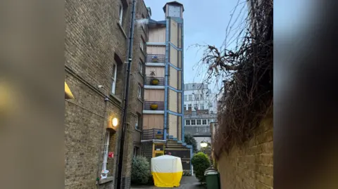 Fiona Jane Garrett The building is shown with boarded up areas and a police investigation tent on the ground floor