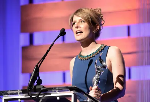 Getty Images Caroline McCall in een blauwe jurk neemt een prijs in ontvangst bij de Costume Designers Guild Awards