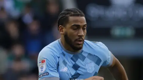 Andy Rinomhota playing for Cardiff City in a light blue away kit