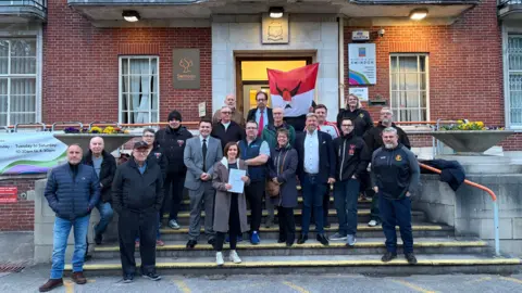 Kate Tomlinson A group of people outside a council building looking at the camera and smiling
