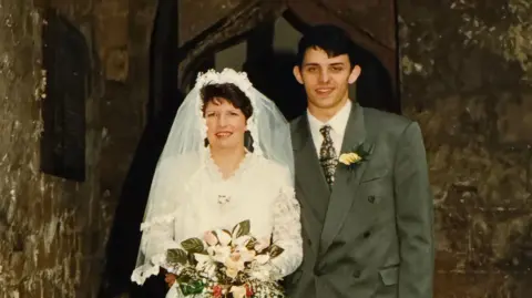 Family An old wedding picture of Yvonne, who is wearing a white wedding dress, and Phil, who is in a grey suit.