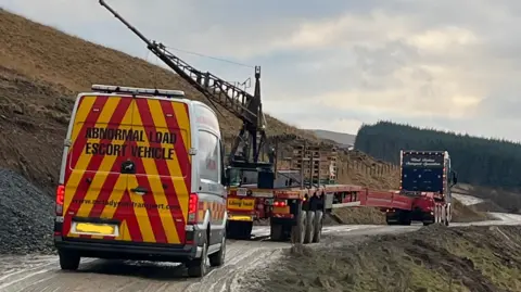 Our Footprints Ltd A rear view of a turbine transporter lorry with and escort van behind it