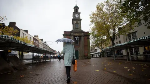Getty Images A woman walking through a market in the centre of the town of Newcastle-under-Lyme
