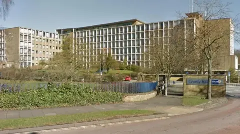 Google Durham County Council HQ. A slightly brutalist, roughly eight story building. Made up of many windows and concrete. It has the look of a 1960s polytechnic.