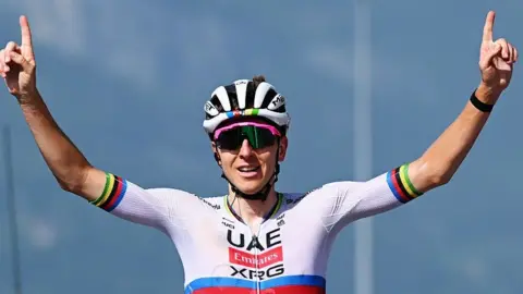 Tadej Pogacar celebrates winning, with both arms raised