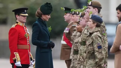 Catherine, Princess of Wales, wear a dark blue coat and hat as she speaks to members of the Irish Guard.