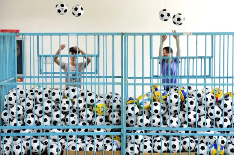 Reuters Employees sort footballs at a company manufacturing sports equipment, in Yiwu, Zhejiang province, China, 5 July 2018