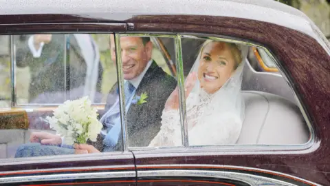 Ben Birchall/PA Wire Harriet Sperling, wearing a white lace gown and veil, and Peter Phillips, in a navy suit with a light blue tie, leave their wedding ceremony at All Saints Church in Kemble, Gloucestershire. 